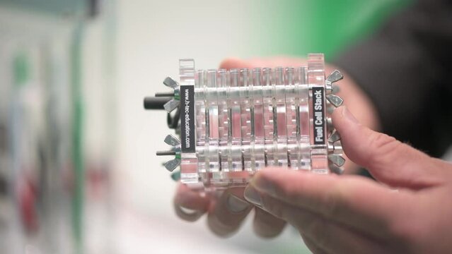 Hands holding a fuel cell stack to generate electricity from hydrogen and air (oxygen)