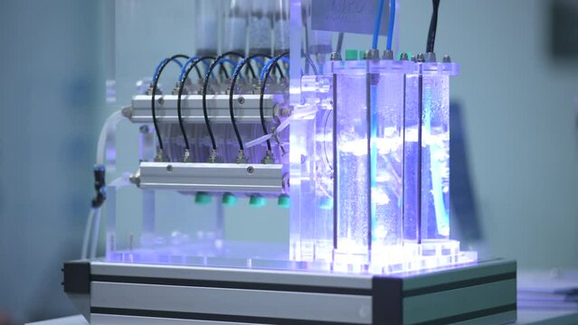 Hydrogen gas bubbles in tubes with water in a electrolyzer demonstrator, blue light, pipes