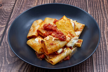 Italian Pasta Paccheri alla Sorrentina with tomato sauce and mozzarella in a plate.