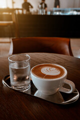 Hot coffee latte with latte art milk foam in cup mug on wood desk on top view. As breakfast In a coffee shop at the cafe,during business work concept