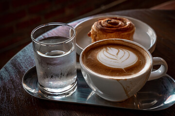 Hot coffee latte with latte art milk foam in cup mug and Homemade Raisin Danish white plate on wood desk on top view. As breakfast In a coffee shop at the cafe,during business work.