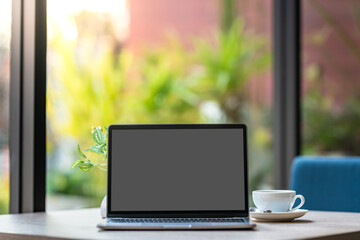 Fototapeta premium Mockup of laptop computer with empty screen with coffee cup on table of the coffee shop background,Black gray screen