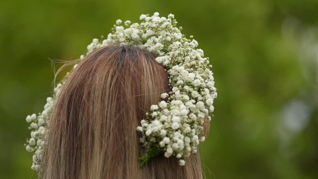 Flower crown made from the bride's flower (Gypsophila elegans) and worn by a women photographed in a beautiful green landscape during an outdoor wedding ceremony. 4k video natural wedding accessories.