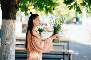 Woman hold a vase of flowers in the street cafe