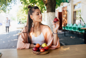 Young beautiful hipster woman sitting in veranda cafe in street.