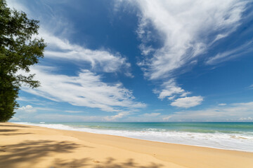 scenery smooth waves from green sea hit on the white long beach..beautiful nature on the beach..white cloud in blue sky background..