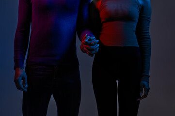 Closeup of young couple holding hands over dark background