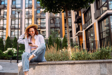 Young lady sitting stairs typing device outside urban city street