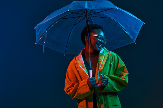 Hipster woman in raincoat with umbrella in neon light