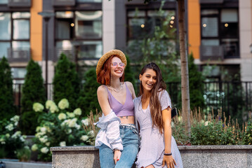 Two young women pose against the background of a building