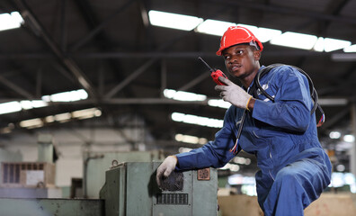 Technician engineer or worker man in protective uniform standing and using walkie talkie radio while controlling work with hardhat and electric cable line at heavy industry manufacturing factory