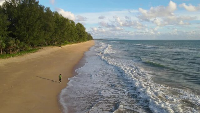 Aerial shot drone follow runer running on beach