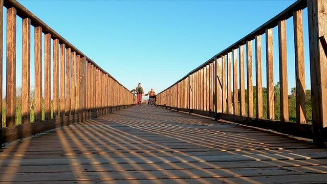 A man in a wheelchair and a woman are walking and holding hands on a wooden walkway at Parque Provincial de Ibera