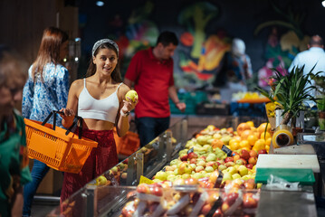 young woman do shopping in supermarket. choosing apples in store