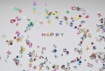 Holiday concept. The word happiness, laid out from letters on a white background, surrounded by cut letters. Background, top view, copy space.