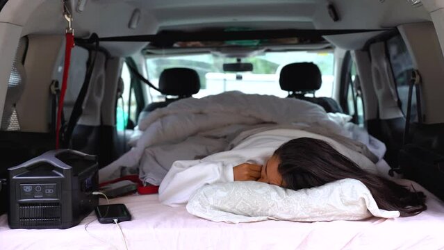 mixed race woman sleeping alone in car camper van living vanlife in remote location