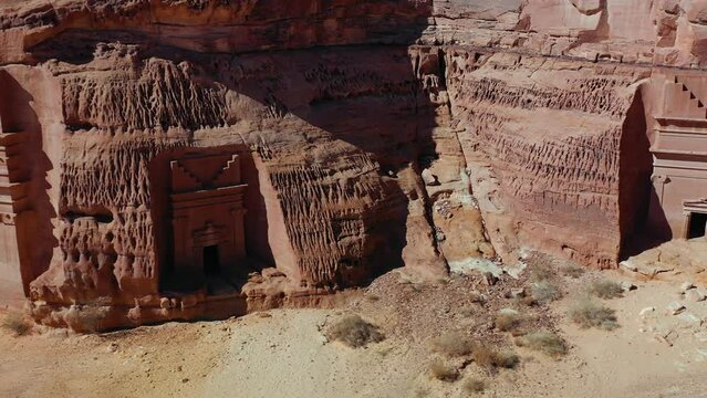 Man walking in front of tombs at the Archaeological Site of Al-Hijr (Mad&acirc;in S&acirc;lih) in Saudi Arabia - aerial view