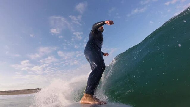 Close up slow motion shot of Handsome guy surfing a green wave in guincho surf spot. strong snap on the end. generating a lot of speed. Guincho, Cascais.