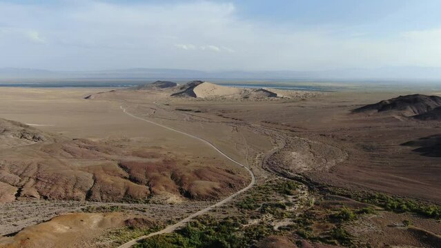 Singing Dunes in Altyn Emel National Park Almaty region, Kazakhstan. Wide drone backwards shot of vast landscape.