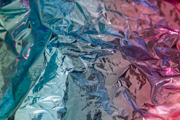 Iridescent foil texture background. Holographic wrinkled surface. Vibrant gradient template for design.