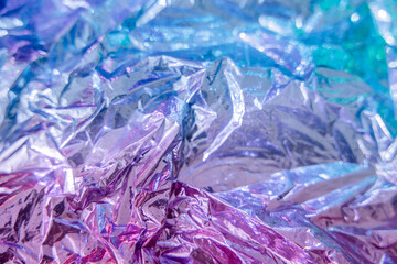 Iridescent foil texture background. Holographic wrinkled surface. Vibrant gradient template for design.