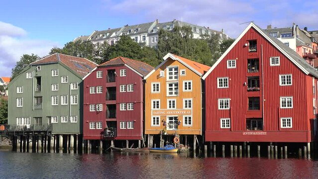 Norway. Colorful residential buildings on the banks of the fjord in Trondheim. Beautiful bright and colorful houses on wooden stilts are built in a row in the water of the bay on a sunny summer day.