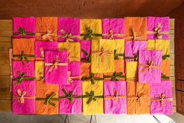 Multi-colored envelopes decorated with ribbons and bows are stacked together on the table, top view. Background image on a greeting and holiday theme