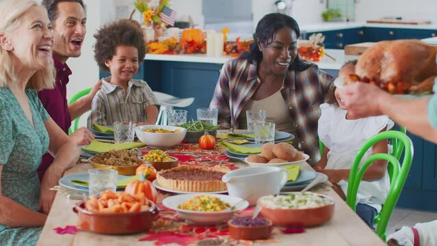 Grandfather serving turkey as multi-generation family celebrate with Thanksgiving meal at home together - shot in slow motion