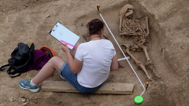 Young archeologist works on an archaeological site at morning sun rays at summer heat