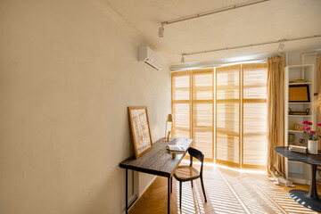 Cozy worplace with wooden table, chair and window blinds on background in bright living room at...