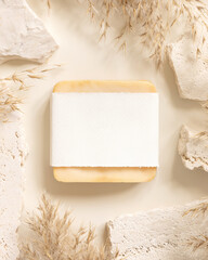 Soap bar with blank label near beige stones and dried pampas grass top view, mockup