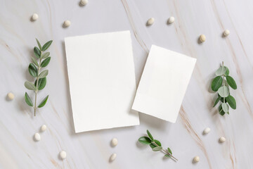 Vertical cards on a marble table decorated with eucalyptus branches top view, Wedding mockup