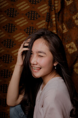 Beauty portrait of happy Asian woman face with natural skin on Indonesian Batik background.