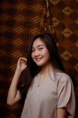 Beauty portrait of happy Asian woman face with natural skin on Indonesian Batik background.