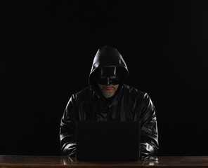 hooded masked hacker with laptop