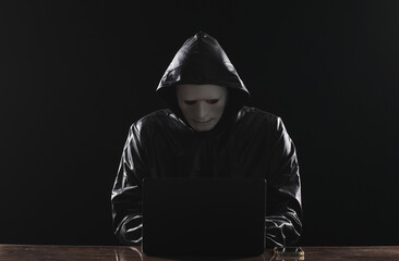 hacker in white mask with laptop