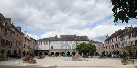 Fototapeta premium Cyclistes sur la place à arcades de Sauveterre de Rouergue dans le Lot
