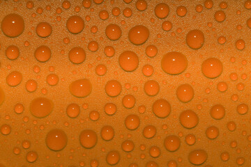 Close-up orange water droplets on shiny orange plastic surface fresh vibrant glittering filling the...