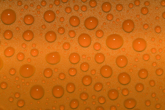 A Close-up Of Orange Water Droplets On A Shiny Orange Plastic Surface Giving A Fresh, Vibrant, Glittering Appearance, Captured In A Studio 