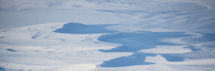 Snow texture. Wind sculpted patterns on snow surface. Wind in the tundra and in the mountains on the surface of the snow sculpts patterns and ridges. Arctic, Polar region. Winter panoramic background.