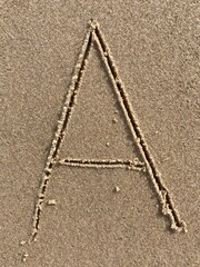 On the beach in the sand is carved the letter A