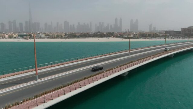 A drone flies over a car traveling on a bridge