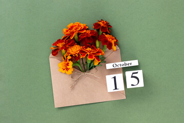 October 15. Bouquet of orange flower in craft envelope and calendar date on green background. Minimal concept Hello fall. Template for your design, greeting card