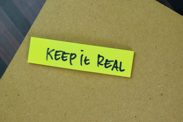 Concept of Keep it Real write on sticky notes isolated on Wooden Table.