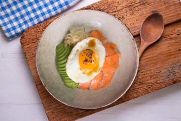 Teriyaki salmon donburi with fried egg, avocado, onion, red pepper and other vegetables. Typical Japanese dish.