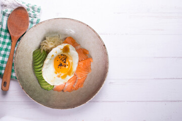 Teriyaki salmon donburi with fried egg, avocado, onion, red pepper and other vegetables. Typical Japanese dish.