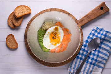 Teriyaki salmon donburi with fried egg, avocado, onion, red pepper and other vegetables. Typical Japanese dish.