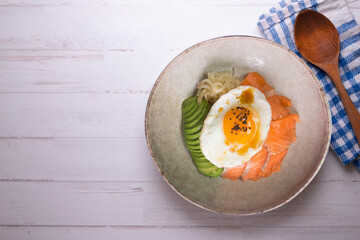 Teriyaki salmon donburi with fried egg, avocado, onion, red pepper and other vegetables. Typical Japanese dish.