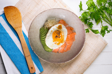 Teriyaki salmon donburi with fried egg, avocado, onion, red pepper and other vegetables. Typical Japanese dish.