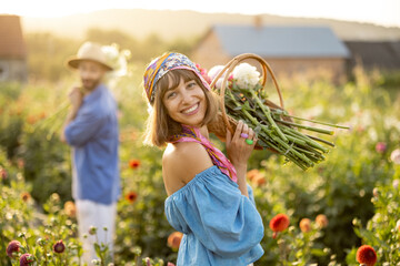 Portrait of a beautiful and cheerful woman as a farmer or gardener holding basket full of freshly...